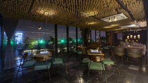 Een restaurant met een bijzonder gestructureerd plafond, grote ramen met uitzicht op buiten en een bar met zitplaatsen.