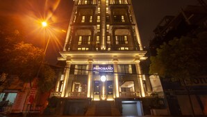 Een hotel met een statig entree, meerdere verdiepingen en verlichte ramen.