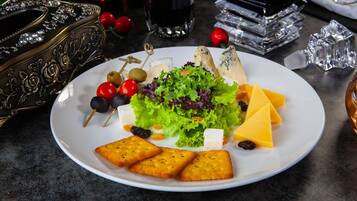 A plate with cheese, grapes, olives, and crackers on a table.