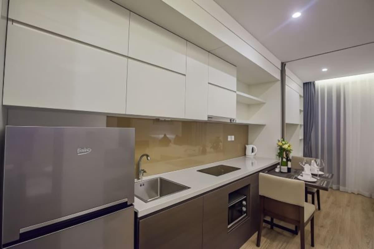 Una cocina moderna con horno empotrado, refrigerador de acero inoxidable y un lavamanos.