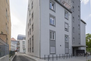 A modern multi-story building with balconies, a gated entrance, and a bicycle parked outside. - Limehome Augsburg (Augsburg)