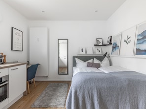 Un dormitorio moderno con cama, mesita de noche y escritorio con silla.