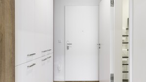 A hallway with a wooden floor, white walls, and a closed door. - Limehome Augsburg (Augsburg)