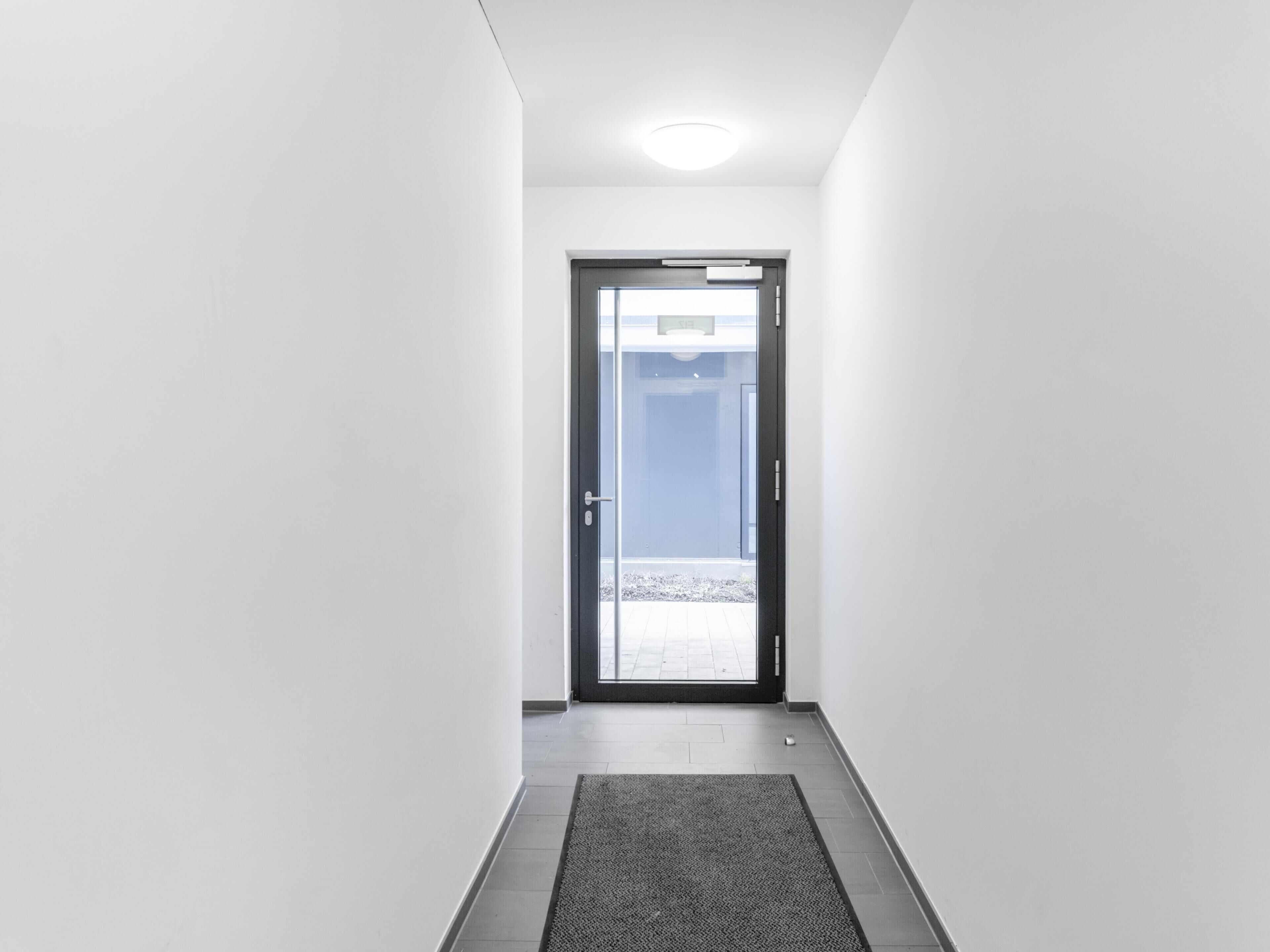 Un pasillo que conduce a una puerta con vista a un patio empedrado.