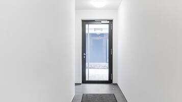 Un pasillo que conduce a una puerta con vista a un patio empedrado.