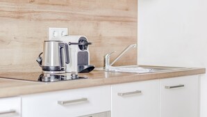 A modern kitchen with white cabinets, a wooden countertop, a coffee maker, a toaster, and an oven. - Limehome Augsburg (Augsburg)