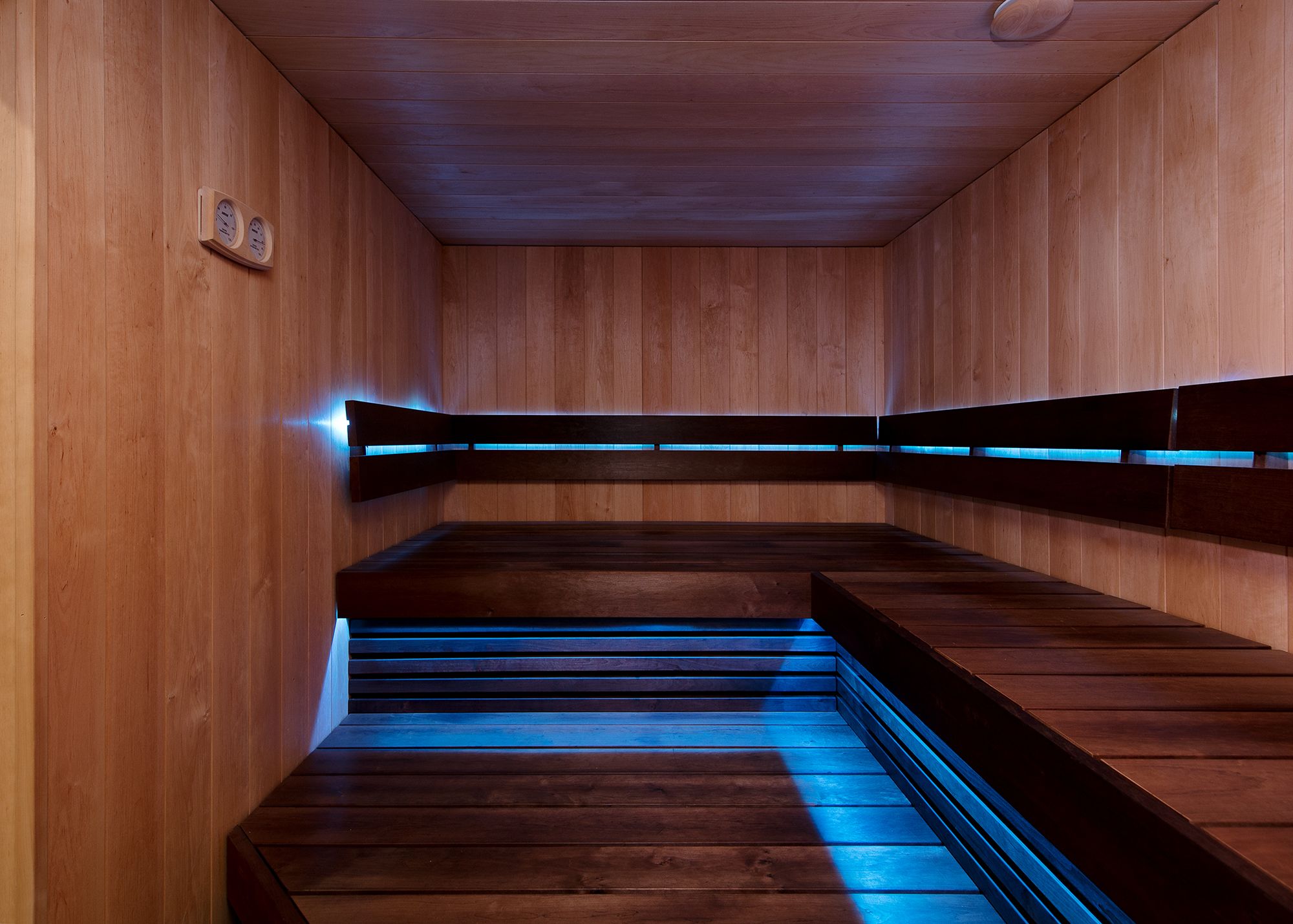 Een sauna met houten banken en een vloer met blauwe verlichting.