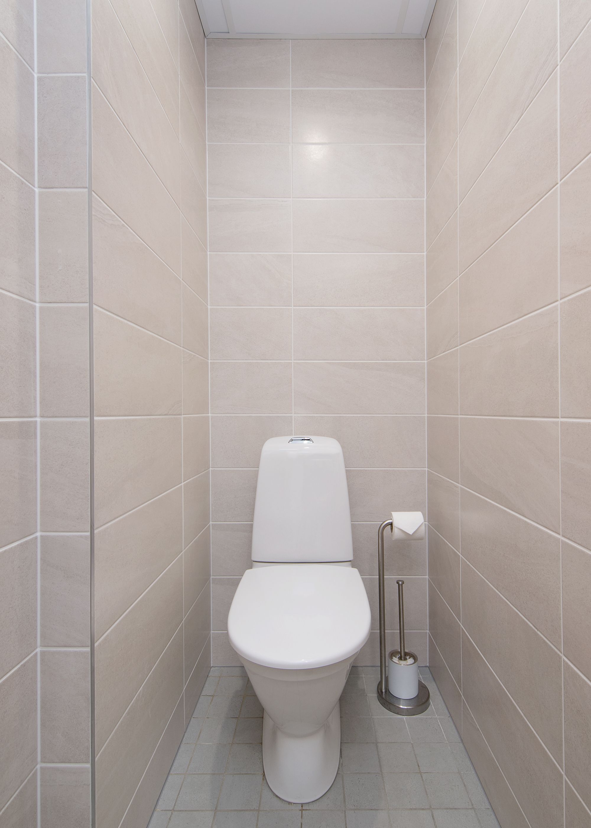 A small, modern bathroom with a toilet, a hand dryer, and a toilet paper holder.