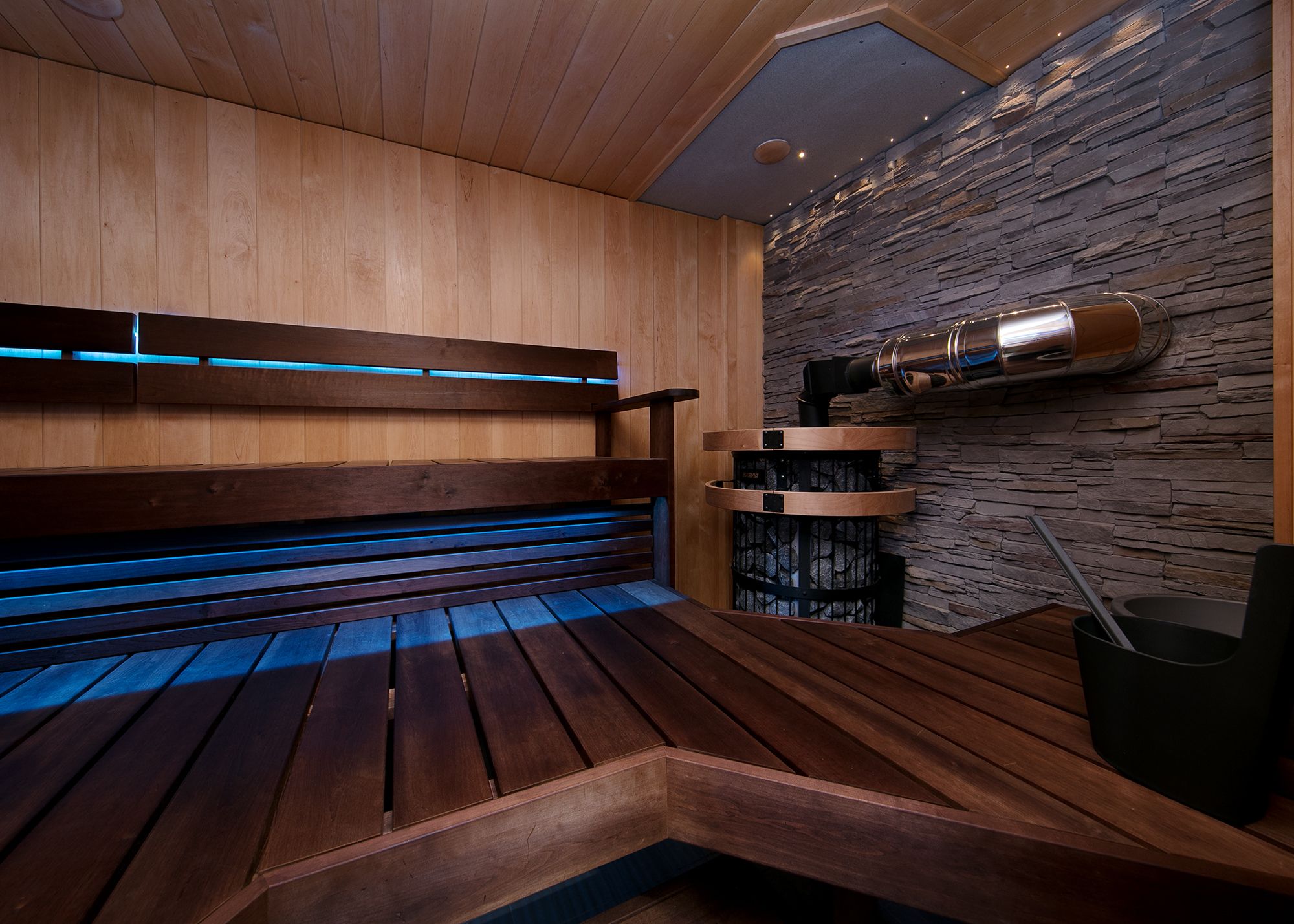 A sauna with wooden benches and a stone wall.