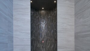 Una ducha moderna con pared vertical texturizada y grifo de cromo.