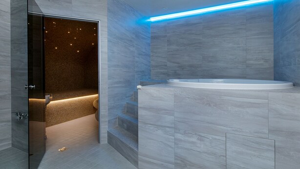 Un baño moderno con bañera, cabina de ducha de vidrio y suelo de mármol.