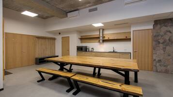 A modern kitchen with a large wooden table and benches, built-in appliances, and a stone accent wall.