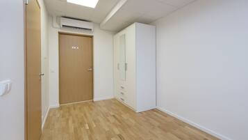 Un couloir avec un plancher en bois, une porte avec une pancarte, une armoire et un appareil de climatisation.
