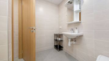 Un baño con puerta de madera, un lavabo con espejo y un inodoro.