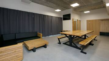 A conference room with a long table, benches, a sofa, and a TV screen.