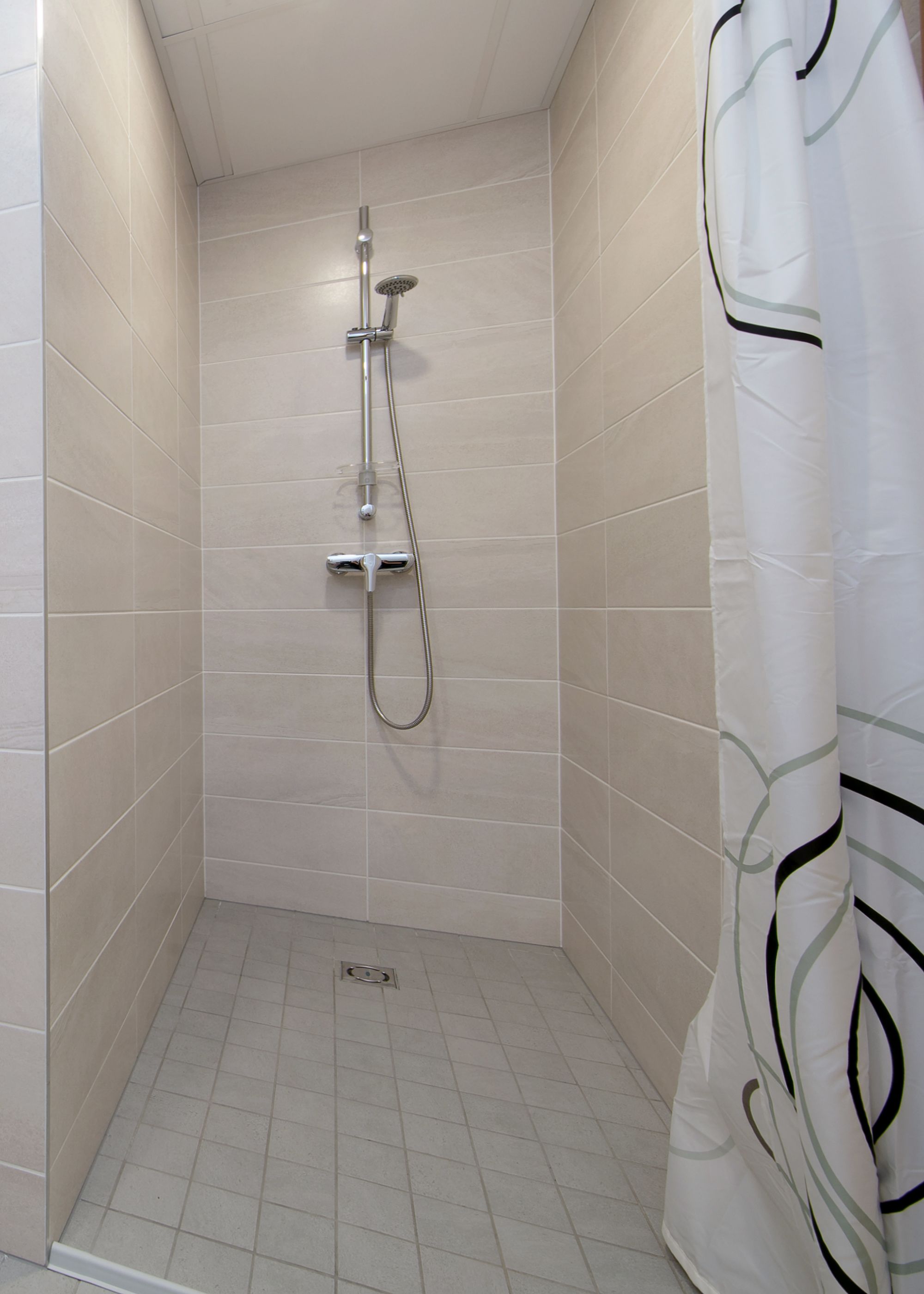 A small, tiled shower area with a showerhead and handheld shower attachment.