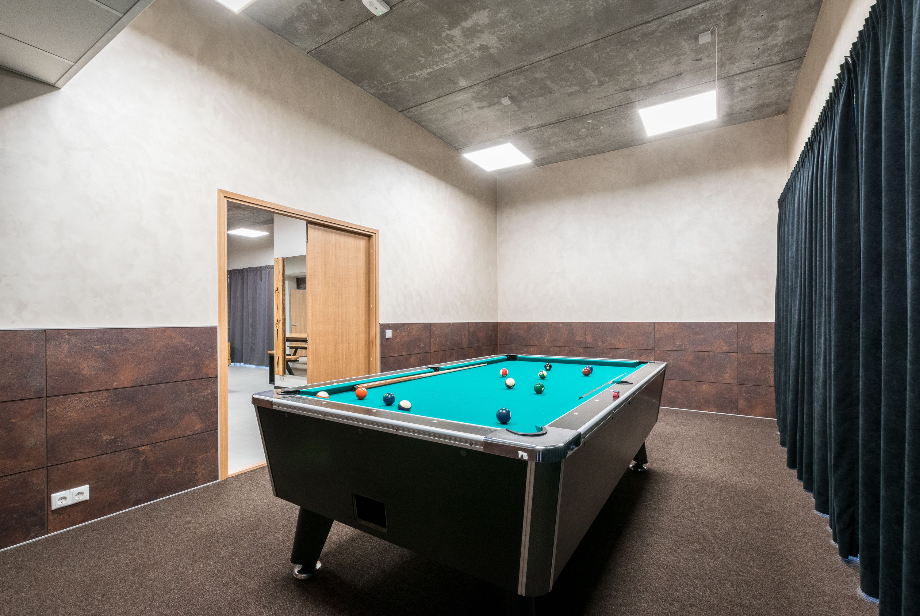 Una mesa de billar en una habitación con piso de baldosas, una puerta y una cortina.