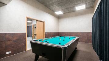 Una mesa de billar en una habitación con piso de baldosas, una puerta y una cortina.