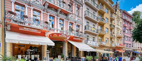 A hotel with a restaurant, antique shop, and outdoor seating area with potted plants.