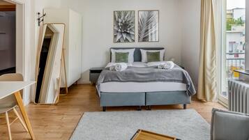 Ein modernes Schlafzimmer mit Bett, Nachttischen, einem Schreibtisch und einem großen Fenster.