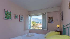 A bedroom with a bed, a window, and artwork on the wall.