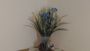 A wooden cabinet with a decorative arrangement on top, including a pine cone, a candle, and a blue ribbon.
