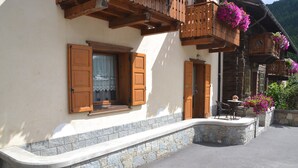 A traditional chalet with wooden balconies, stone steps, and outdoor seating.