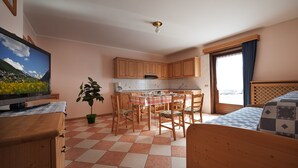 A compact room with a kitchen area, a dining table, and a bed.