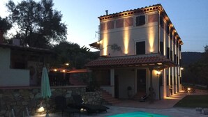 A two-story building with a swimming pool, outdoor seating, and a stone wall. - Casale Olea (Massarosa)