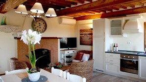 A cozy living space with a dining area, kitchen, and entertainment setup. - Casale Olea (Massarosa)