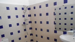 Een badkamer met douche, toilet en wastafel.