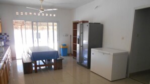 Een kamer met een bed, een koelkast, een tafeltje en een prullenbak.