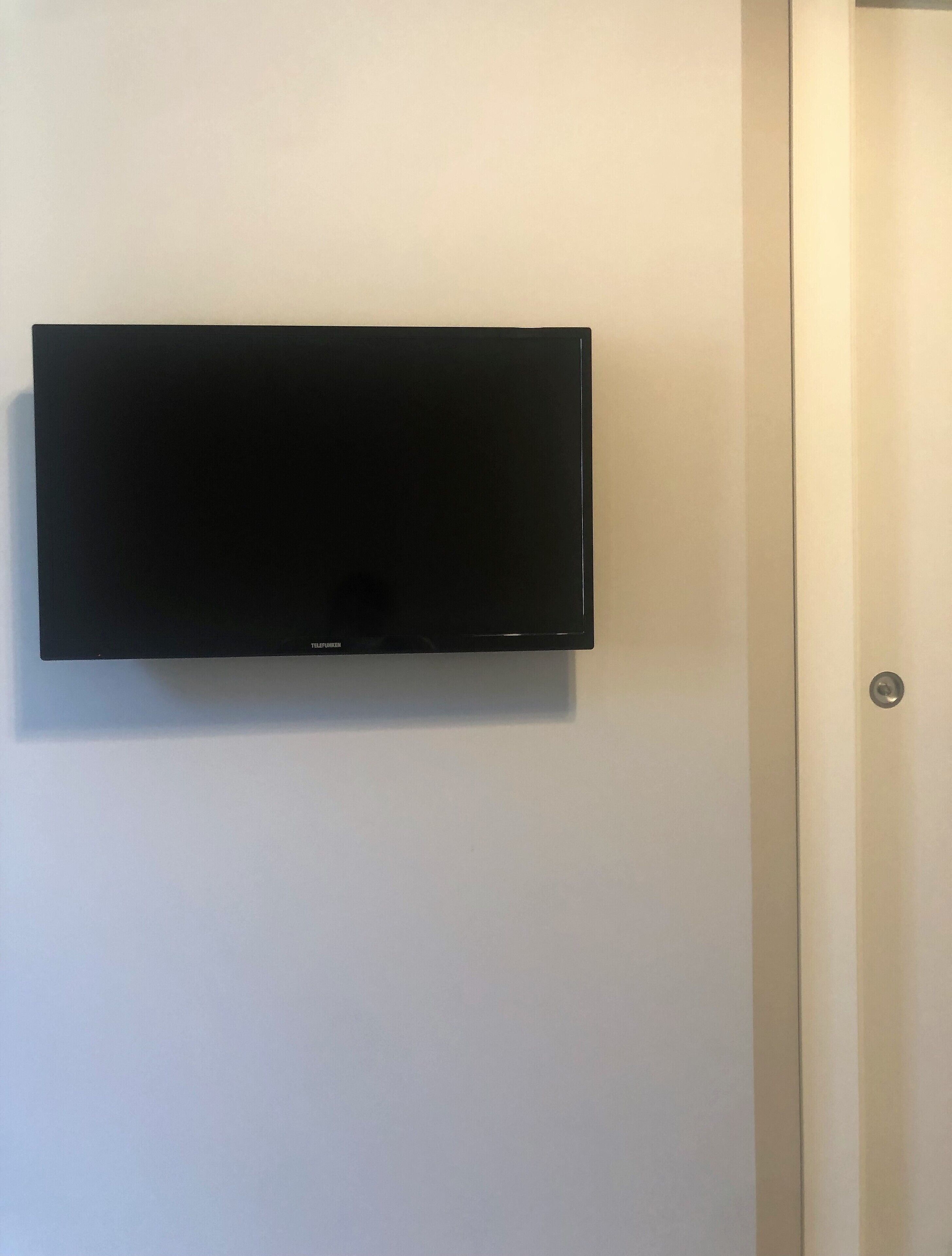 Un televisor de pantalla plana montado en una pared blanca en una habitación.