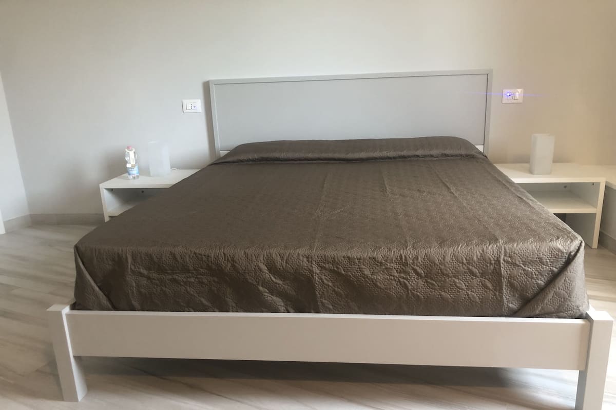 Un dormitorio con cama, mesitas de noche y una mesilla auxiliar.