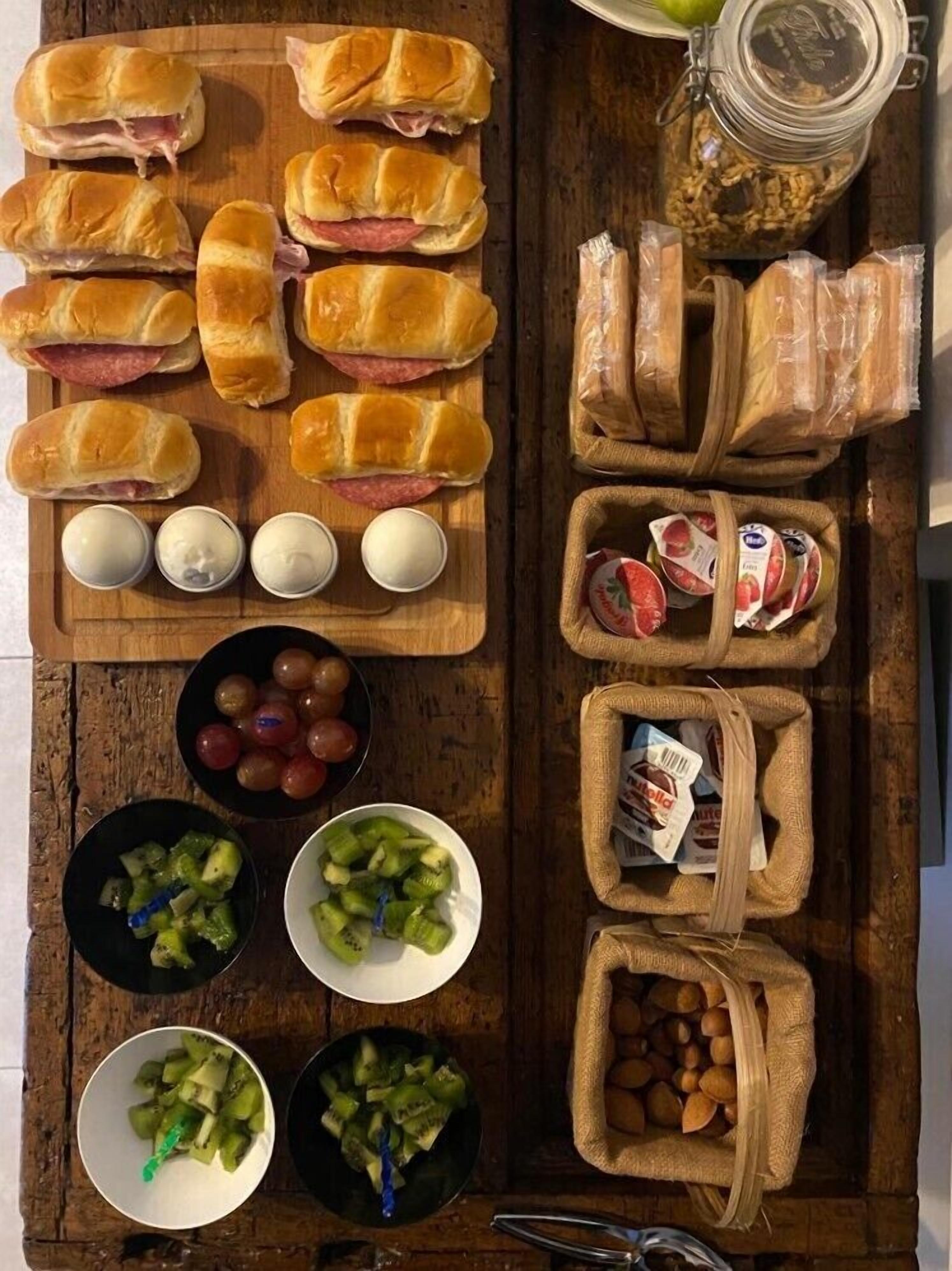 Une table en bois sur laquelle on trouve divers aliments, notamment des sandwichs, des œufs, des raisins et des légumes.