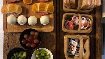 Une table en bois sur laquelle on trouve divers aliments, notamment des sandwichs, des œufs, des raisins et des légumes.