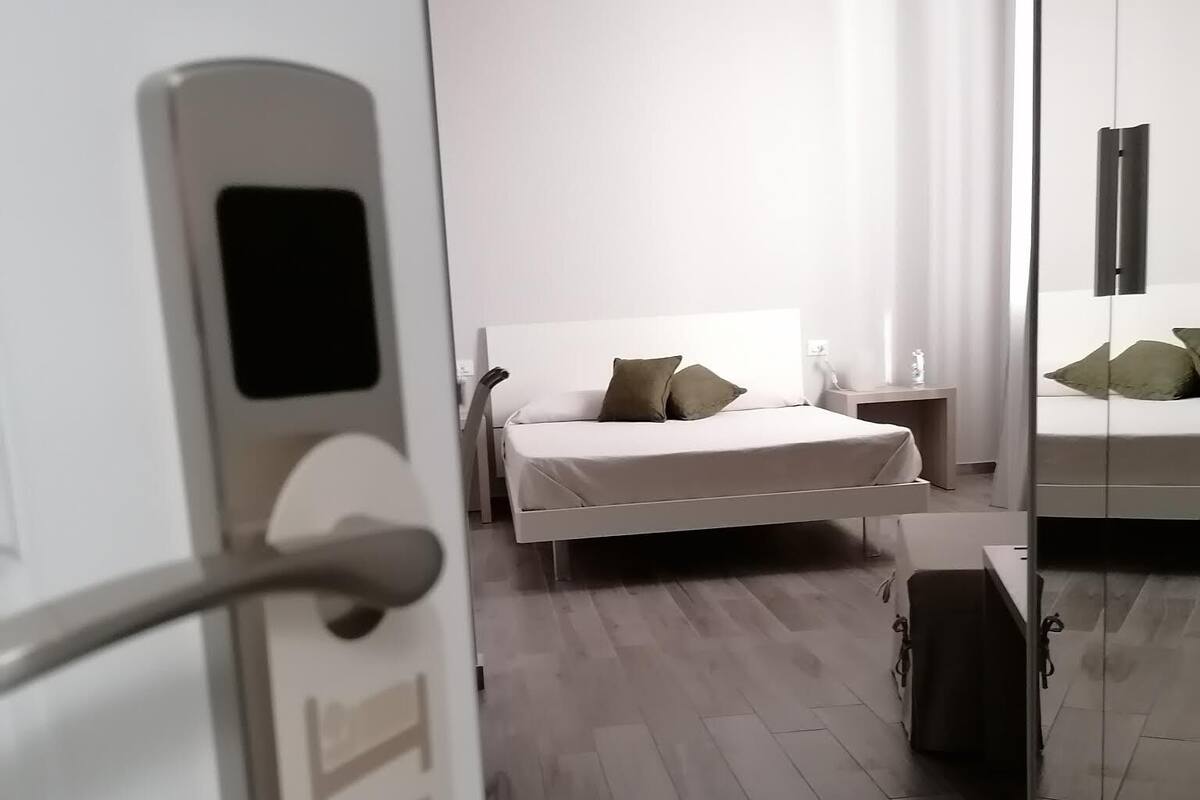 Una habitación de hotel moderna con cama, mesita de noche y espejo.