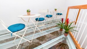 Um interior moderno com escada de vidro, cadeiras brancas com almofadas azuis e pequenas plantas em vasos.