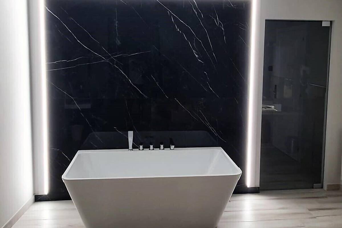 Un baño moderno con una bañera independiente, cabina de ducha de cristal y salpicadero de mármol.