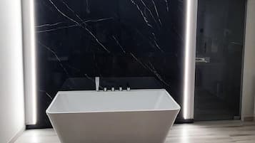 Une salle de bain moderne avec une baignoire sur pieds, une douche à parois de verre et un pare-baignoire en marbre.