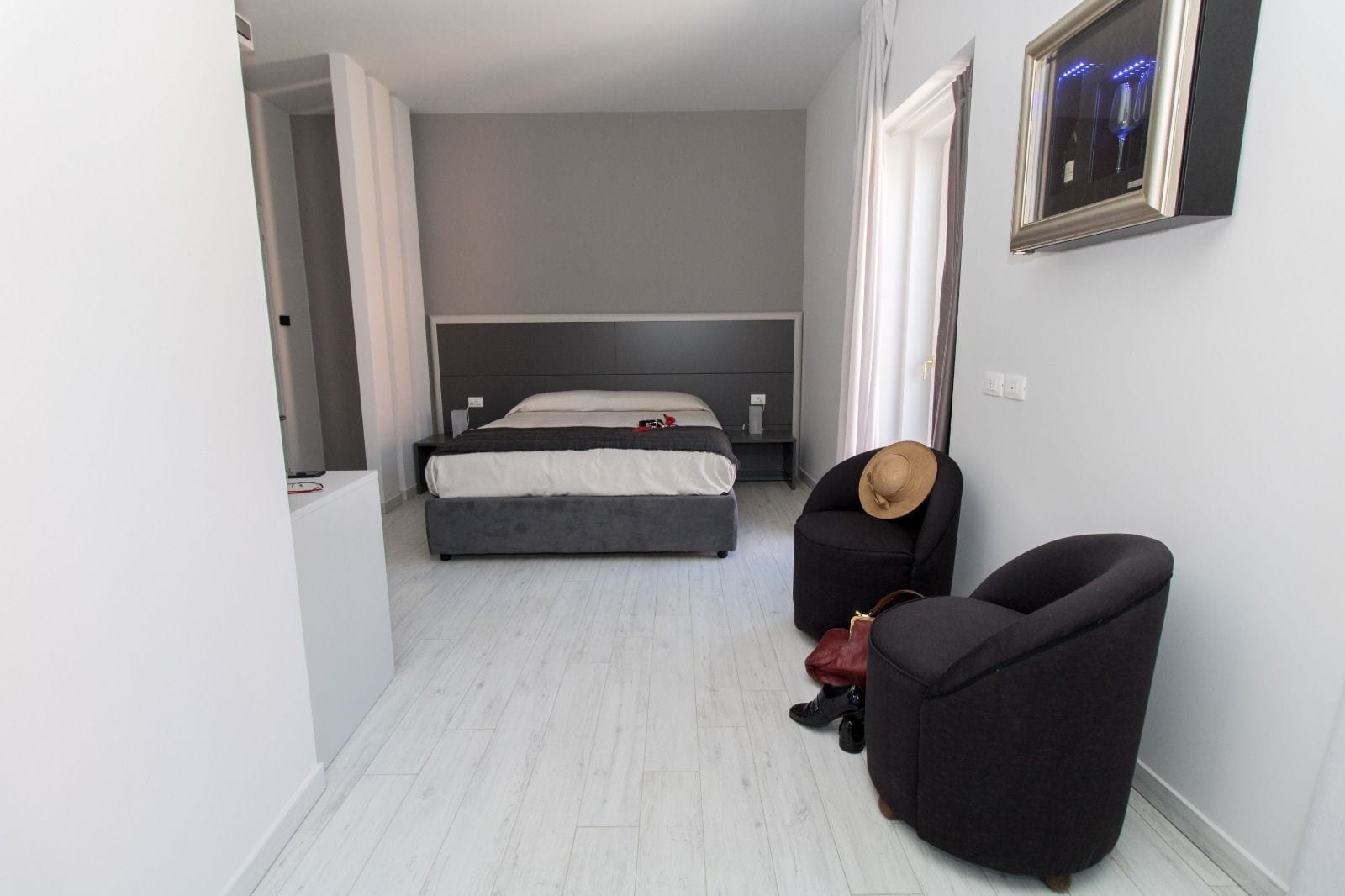 Un pasillo estrecho que conduce a un dormitorio con una cama, una silla y un bolso de mano.