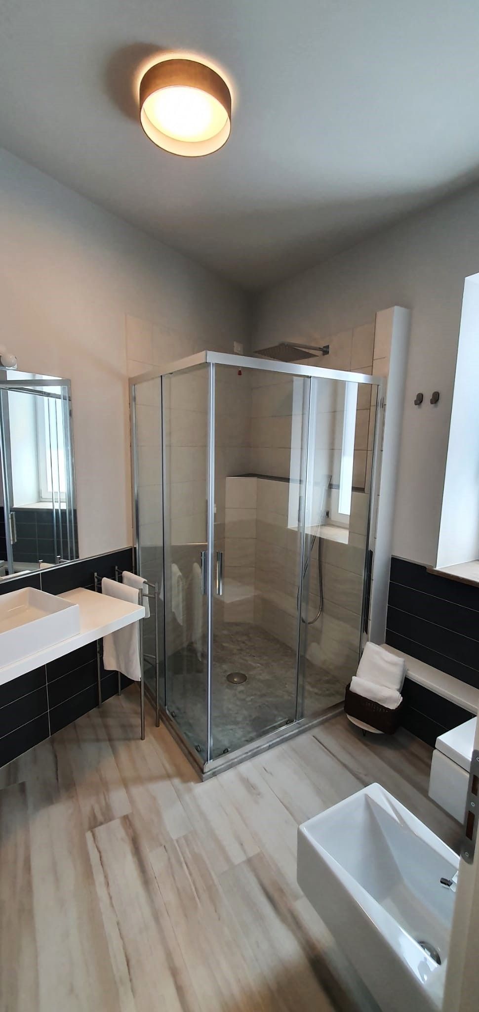 Une salle de bain moderne avec une douche à parois de verre, un lavabo blanc et un grand miroir.