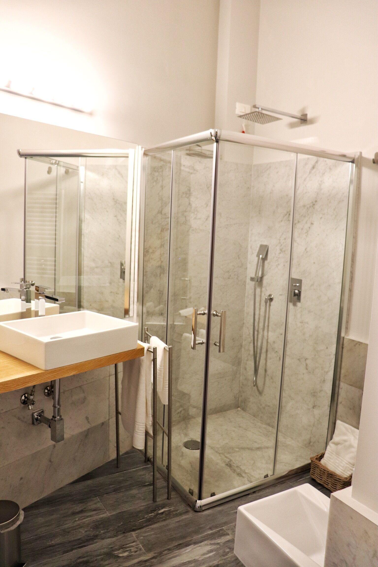 A modern bathroom with a glass-enclosed shower, a white sink, and a bathtub.