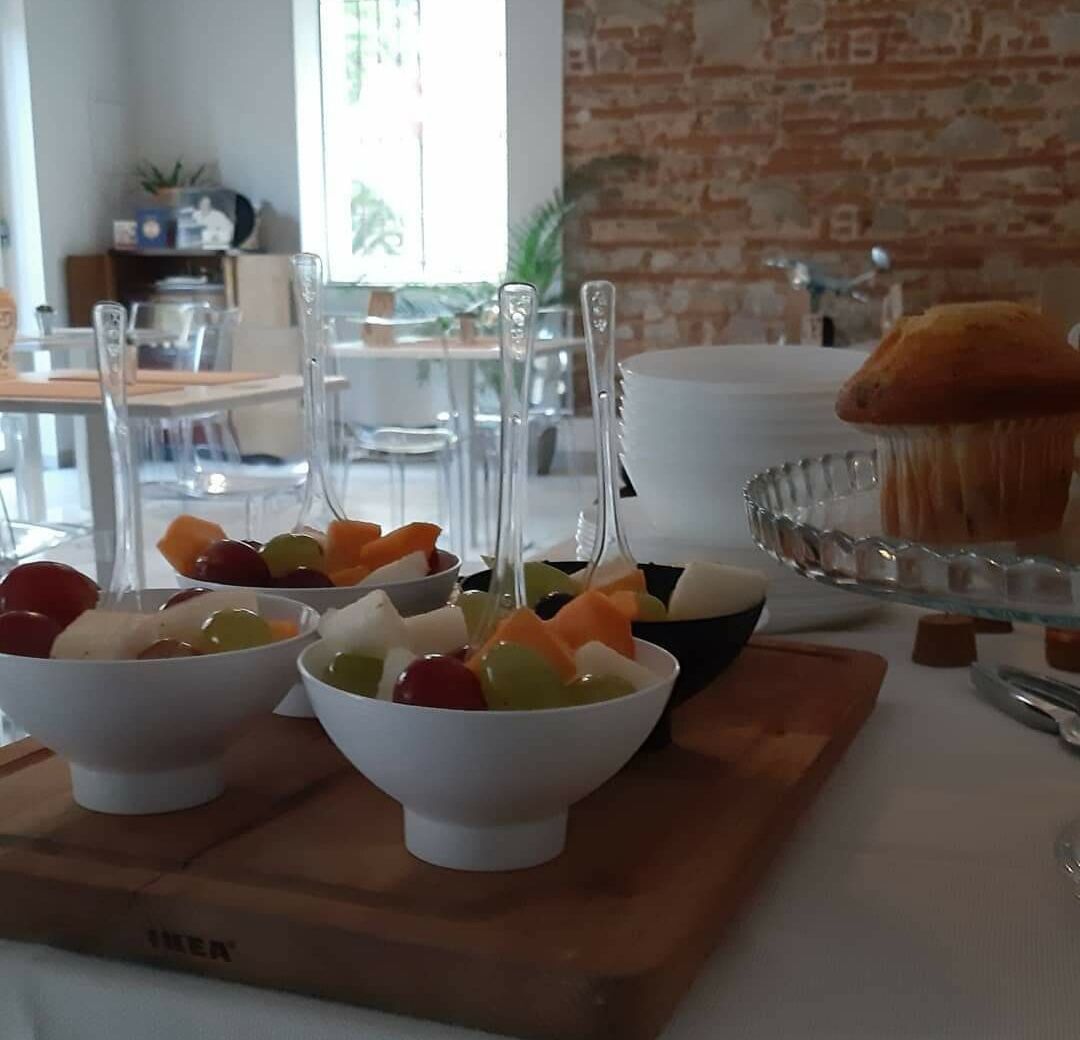A dining area with white bowls containing fruit, a glass cake stand with a muffin, and IKEA-branded furniture.