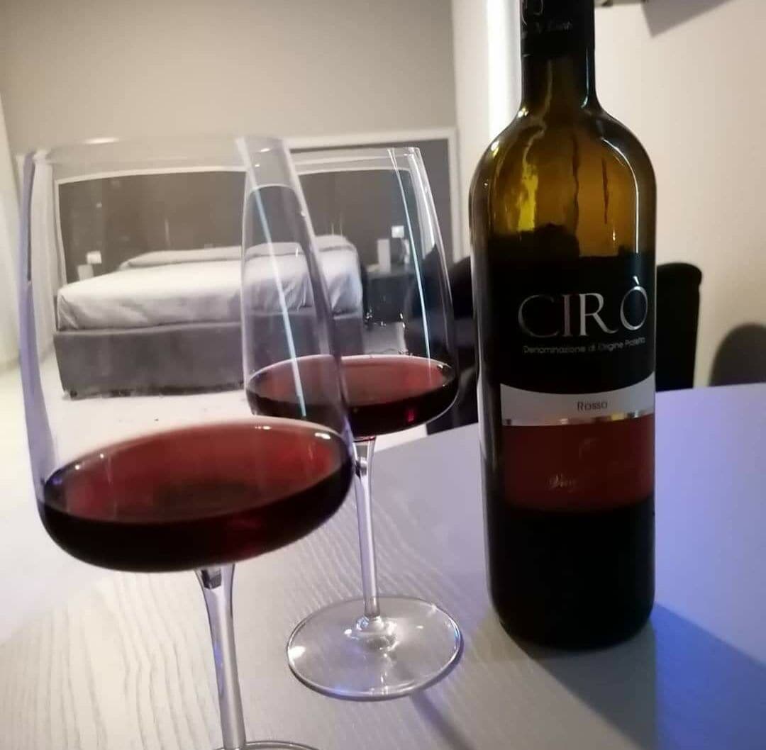 Eine Flasche Ciro-Wein und zwei Gläser Rotwein auf einem Tisch.