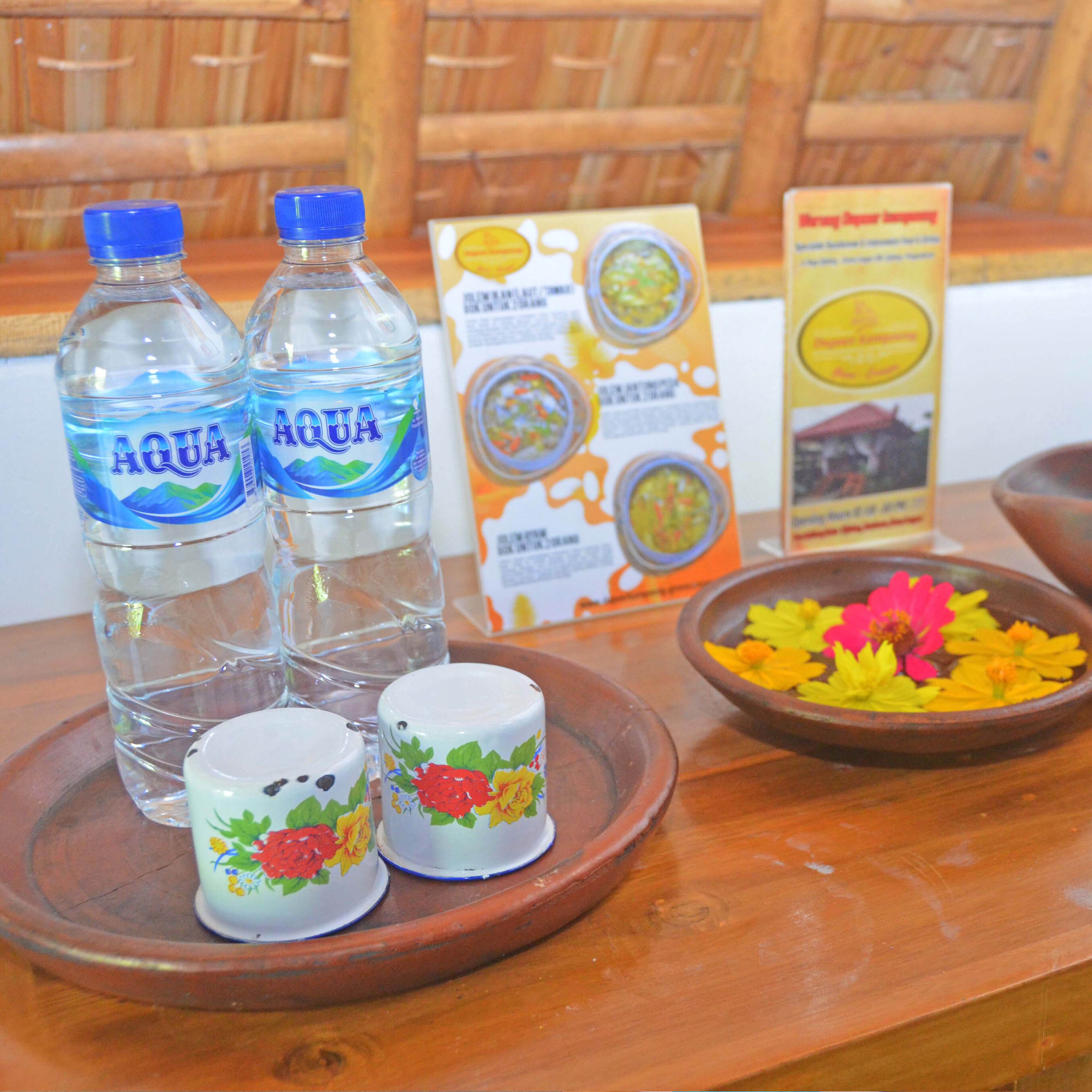 A table with two water bottles, a box of food, and a bowl with flowers.