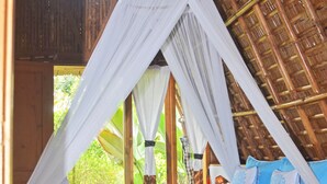 A bed with a canopy, a blue bedspread, and pillows. - Lagoona Beach Bungalows (Cijulang)