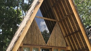 A thatched-roof structure with a triangular window design, wooden flooring, and a hammock. - Lagoona Beach Bungalows (Cijulang)
