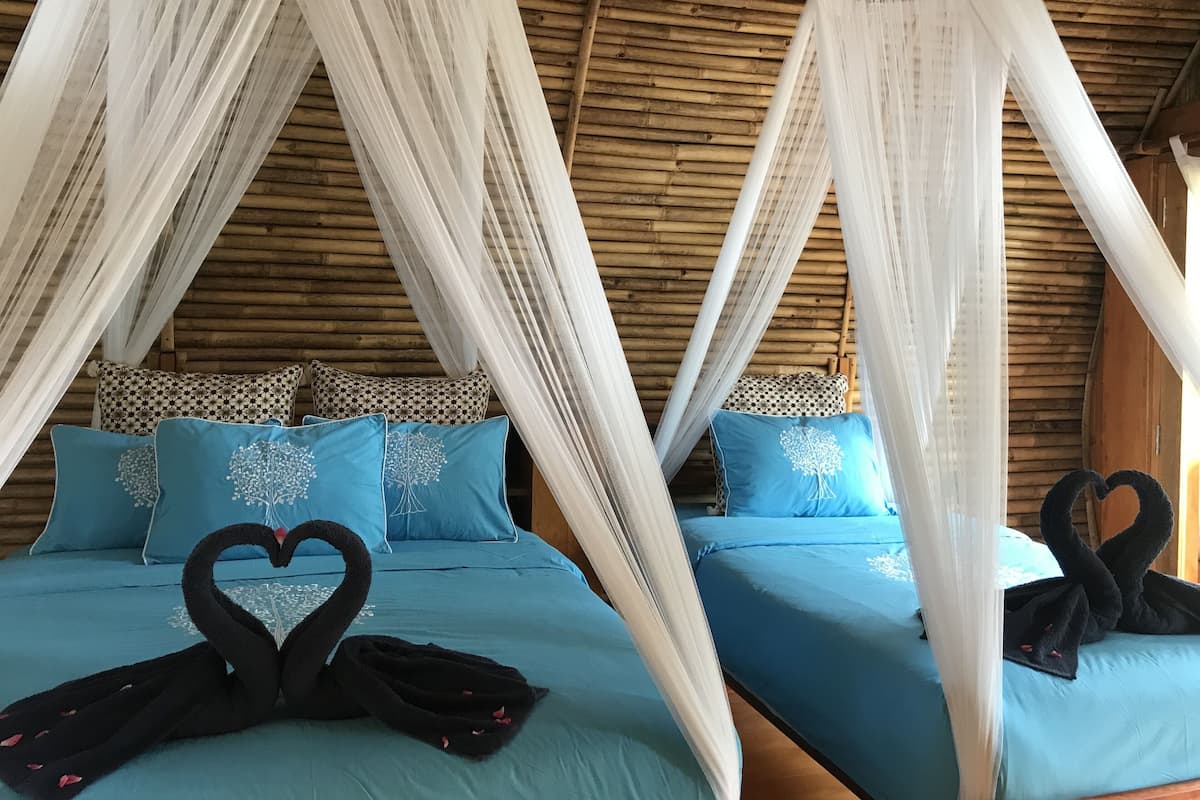 Een kamer met twee bedden, elk voorzien van een hemelbed en blauw beddengoed.