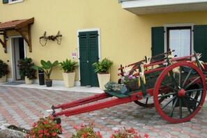 A yellow building with a red carriage parked in front. - Agritur Girasole (Arco)